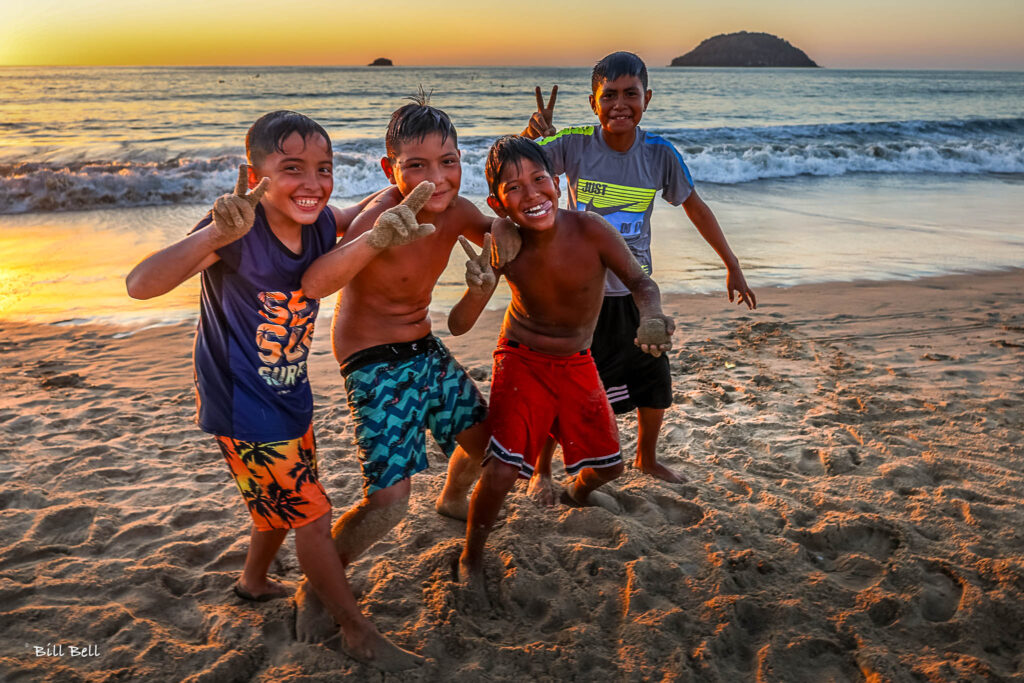 Joyful Friends at Sunset "A group of local children poses with cheerful energy as they play on the beach at sunset, capturing the joy and carefree spirit of Rincón de Guayabitos.