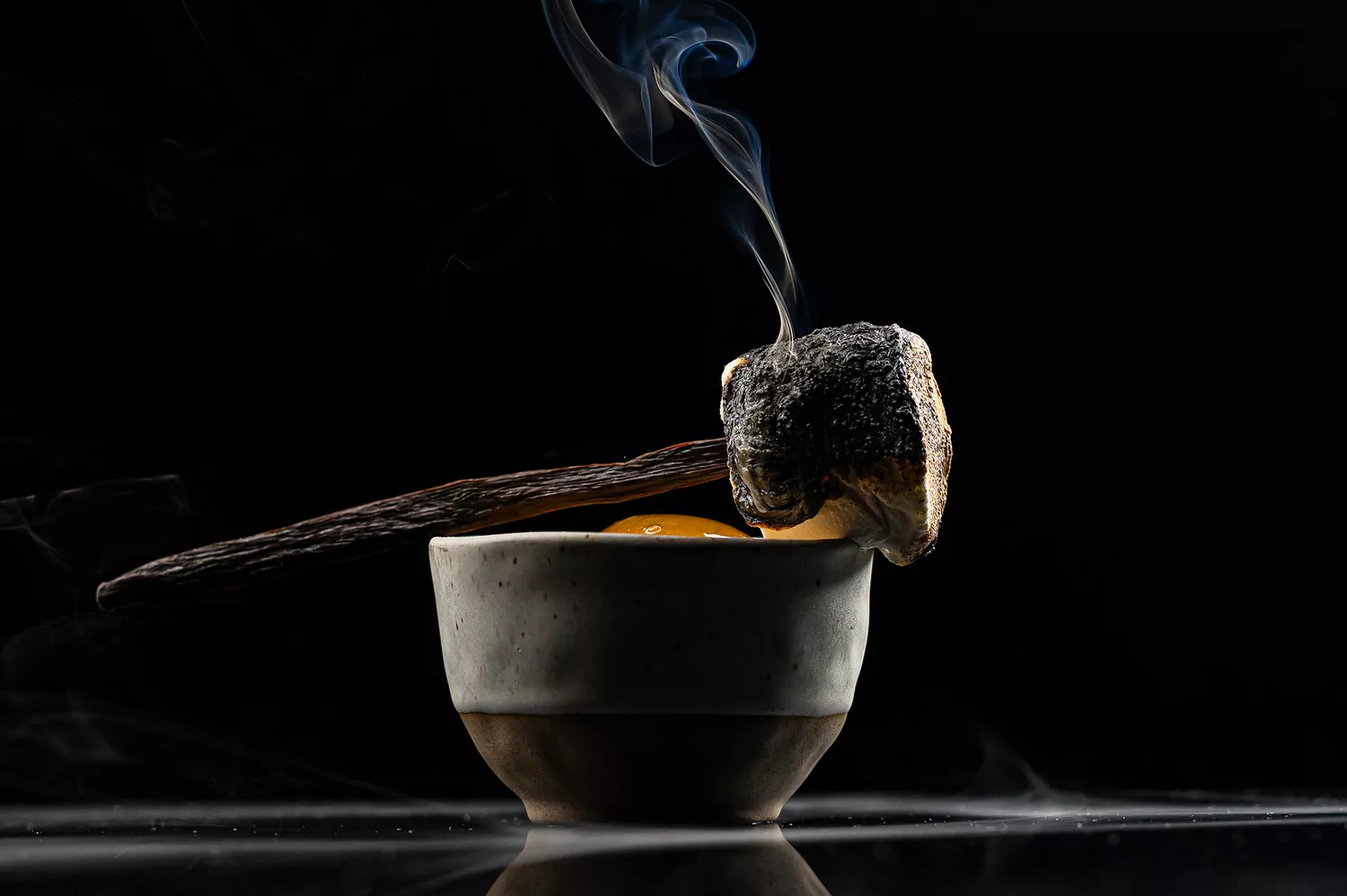 A cocktail with a garnish smoking on top served in a cup