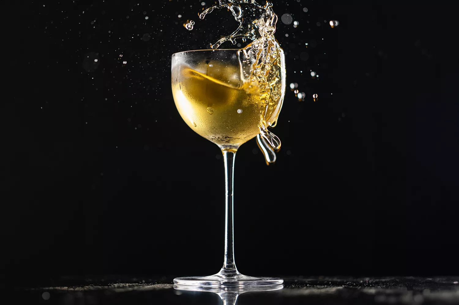 Cocktail glass with liquid splash against black background