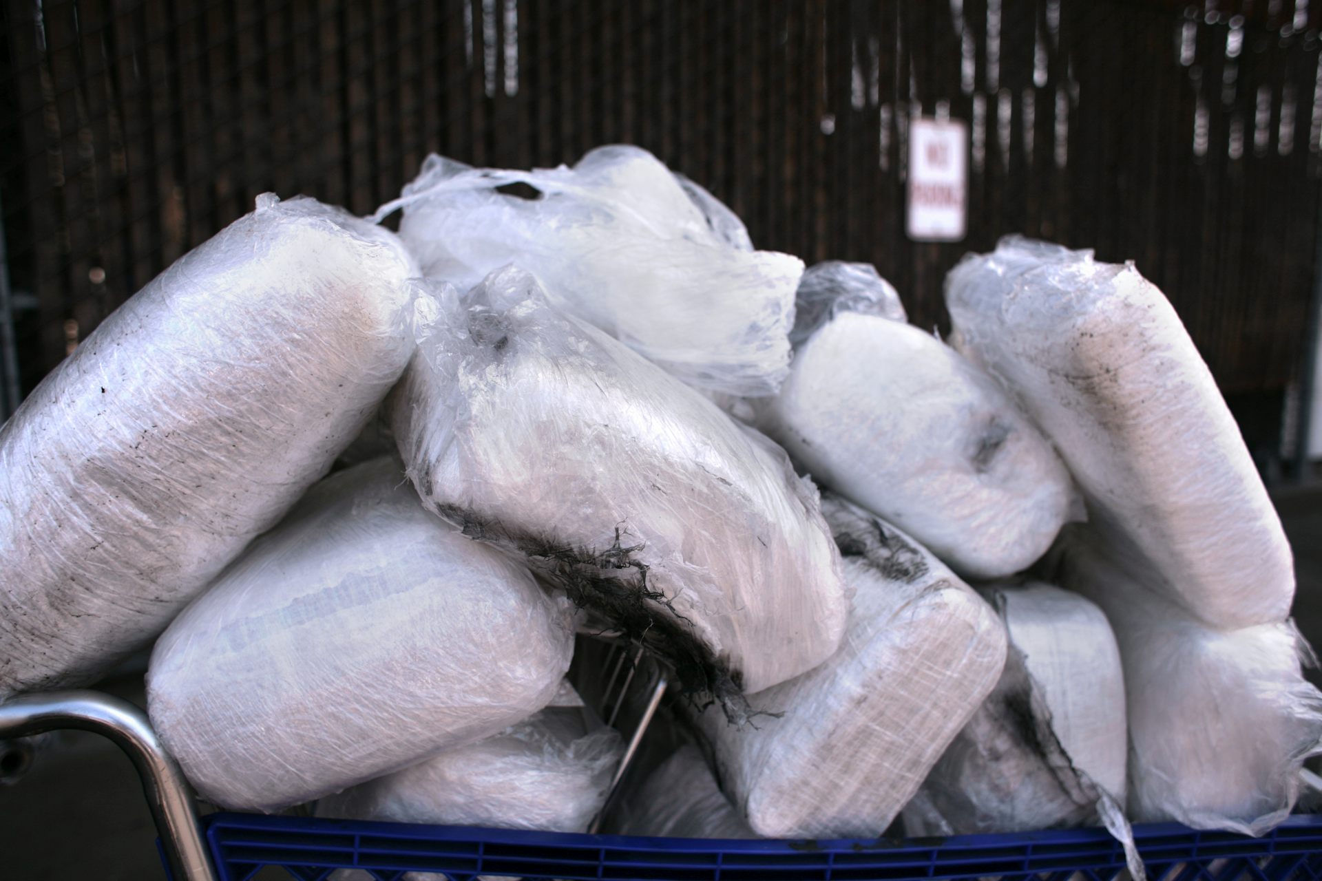 Bags of white power are piled up on a cart.